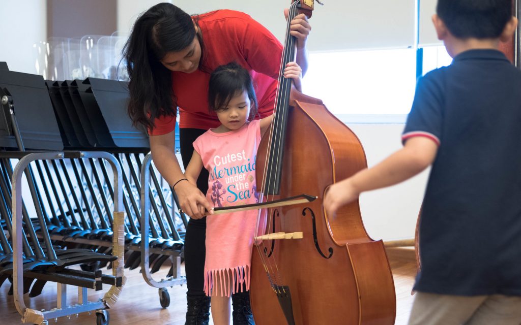 Year 3 student Dahlia Neniel introducing the double bass to a young participant
